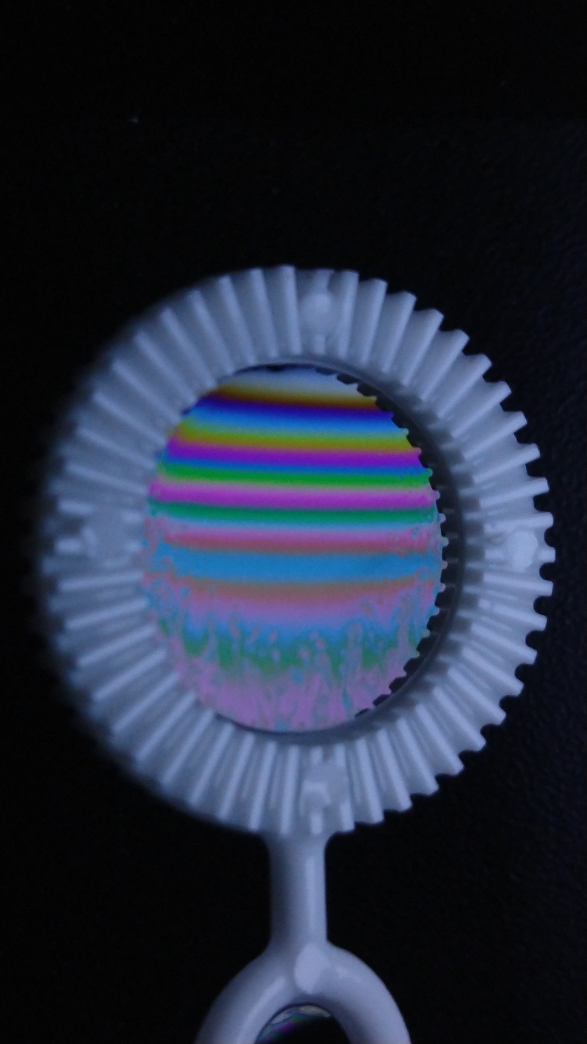 Soap film in a circular holder, showing horizontal colored interference bands